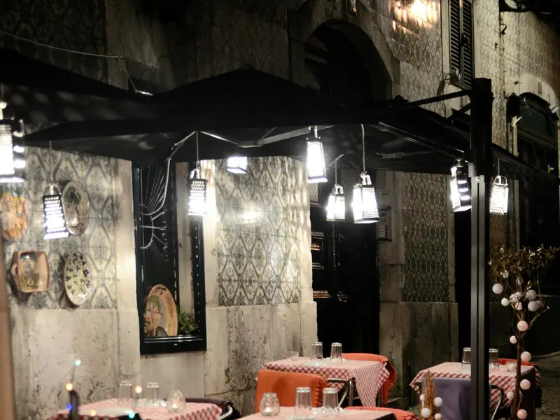 Lisbon street with restaurant tables at night (symbol image)